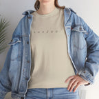 Person wearing a beige t-shirt with 'SHAZOO' text and a denim jacket indoors.